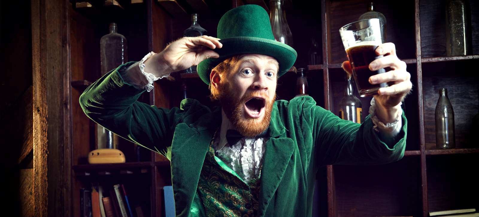 Mann mit irischem Outfit hält ein Glas in der Hand